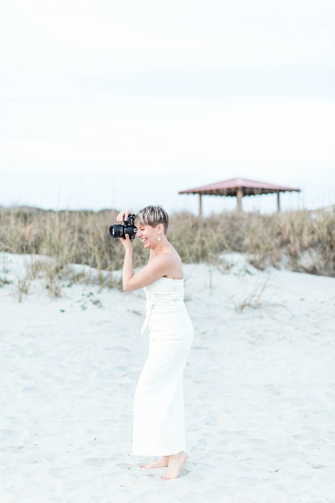 Side portrait of photographer holding camera taking a picture at the beach