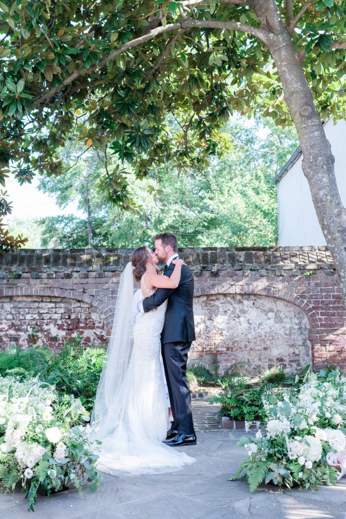 couple kiss at outdoor courtyard ceremony in Charleston