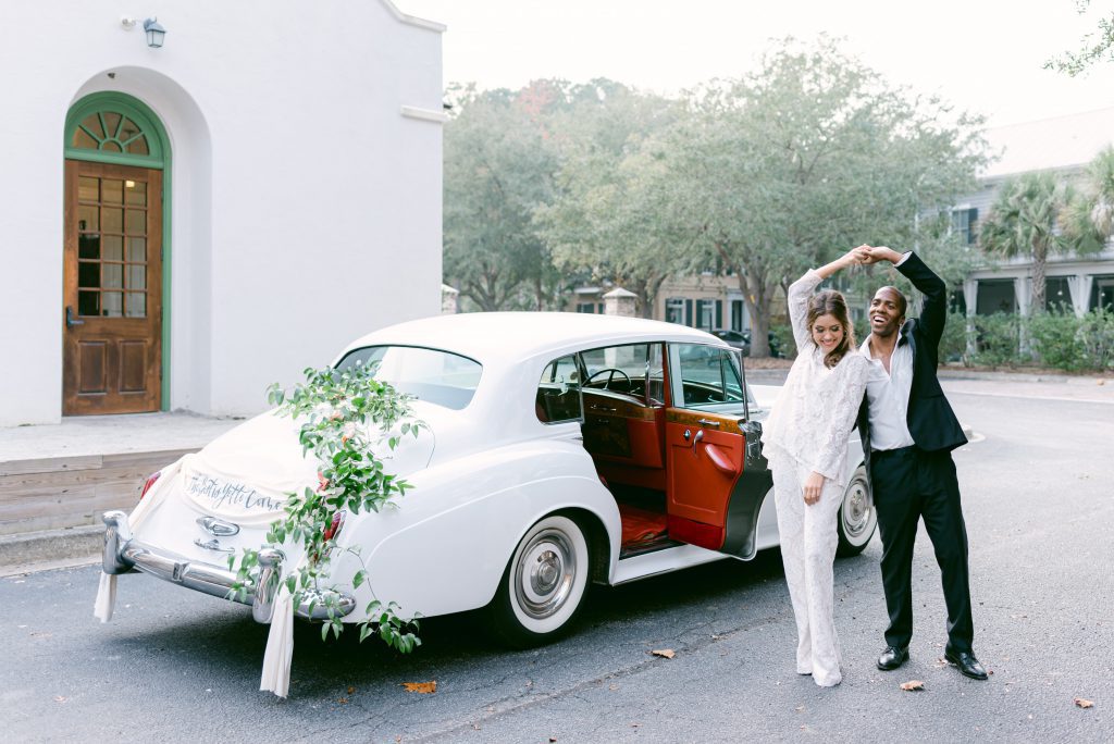 newlyweds twirl in front of getaway car