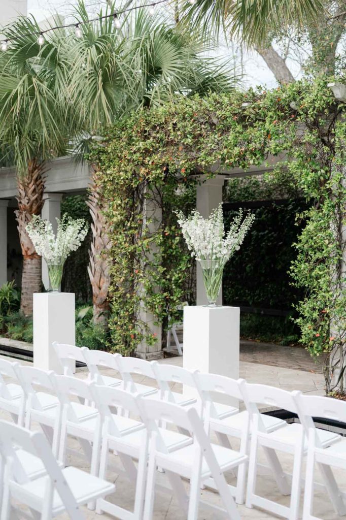 Cannon Green Wedding Ceremony Setup with white chairs and white columns with two large vases