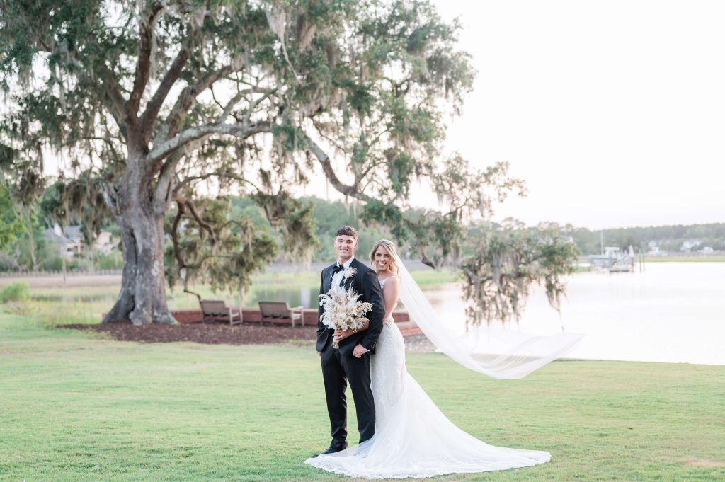 Newlyweds pose by creek at Dunes West