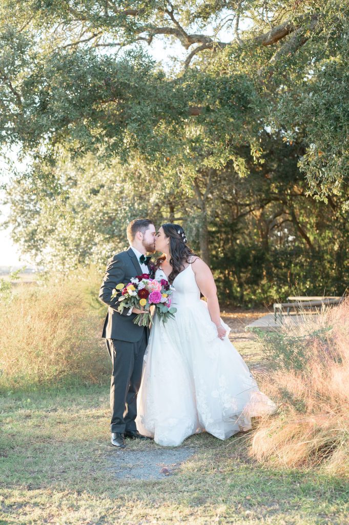 newlyweds kiss next to marsh