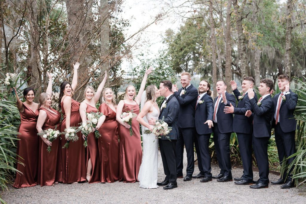 Wedding party cheer the bride and groom as they kiss
