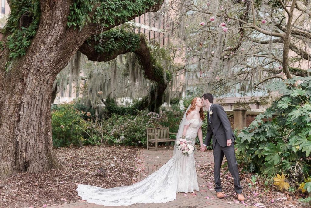 Red headed bride kisses groom in church courtyard