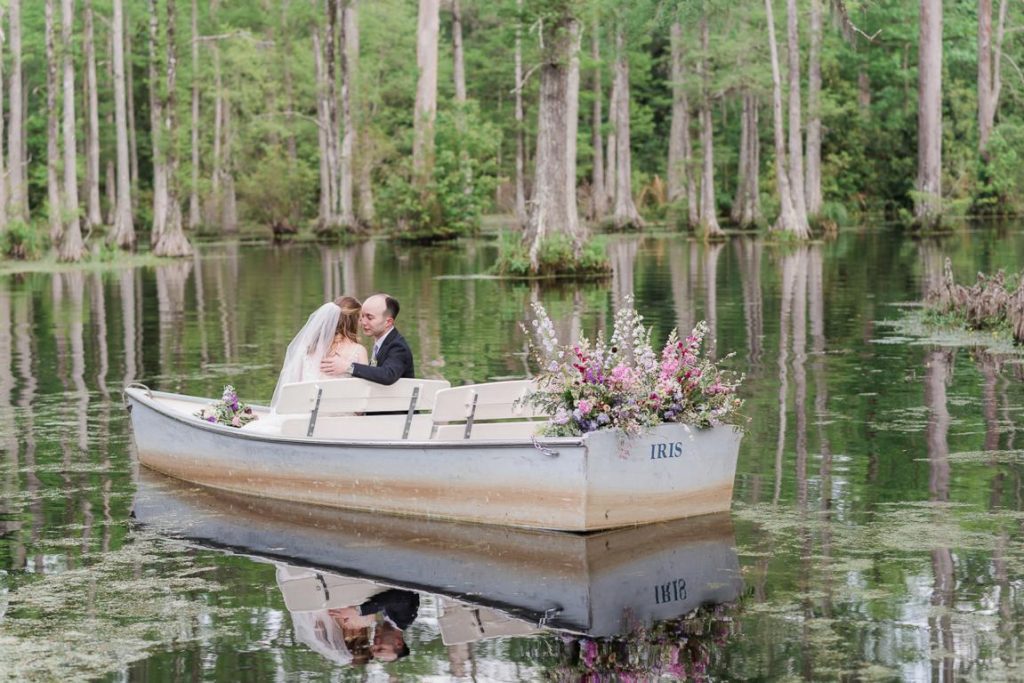 bride and groom snuggle on rowboat decorated with flowers in cypress swap