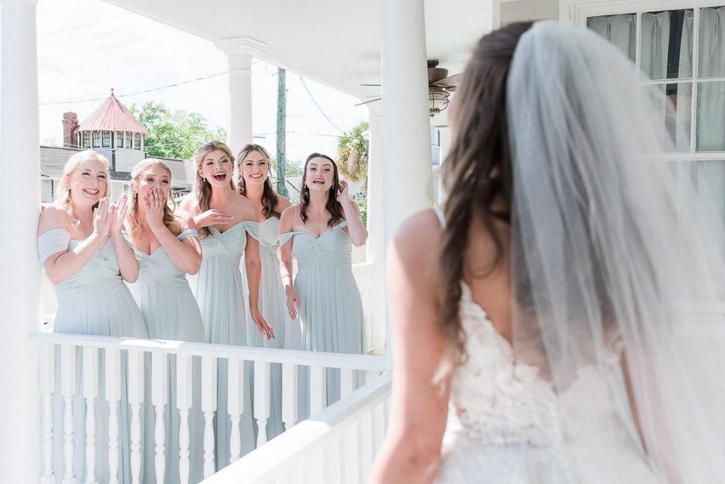 first look with bridesmaids in pale blue dresses on top porch