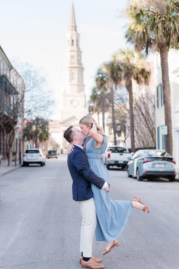 guy lifting girl off her feet and kissing her with church steeple in background