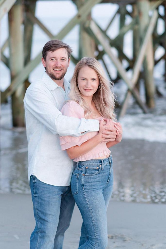 Guy with arms wrapping around girlfriend at beach