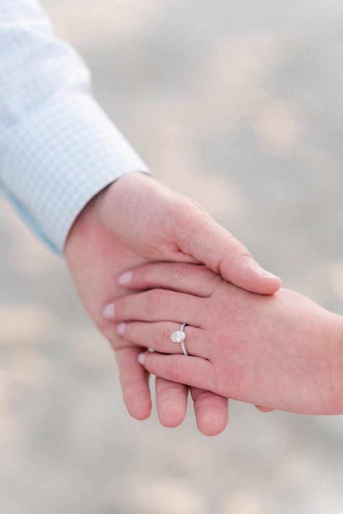 close up of hands with woman wearing an engagement ring