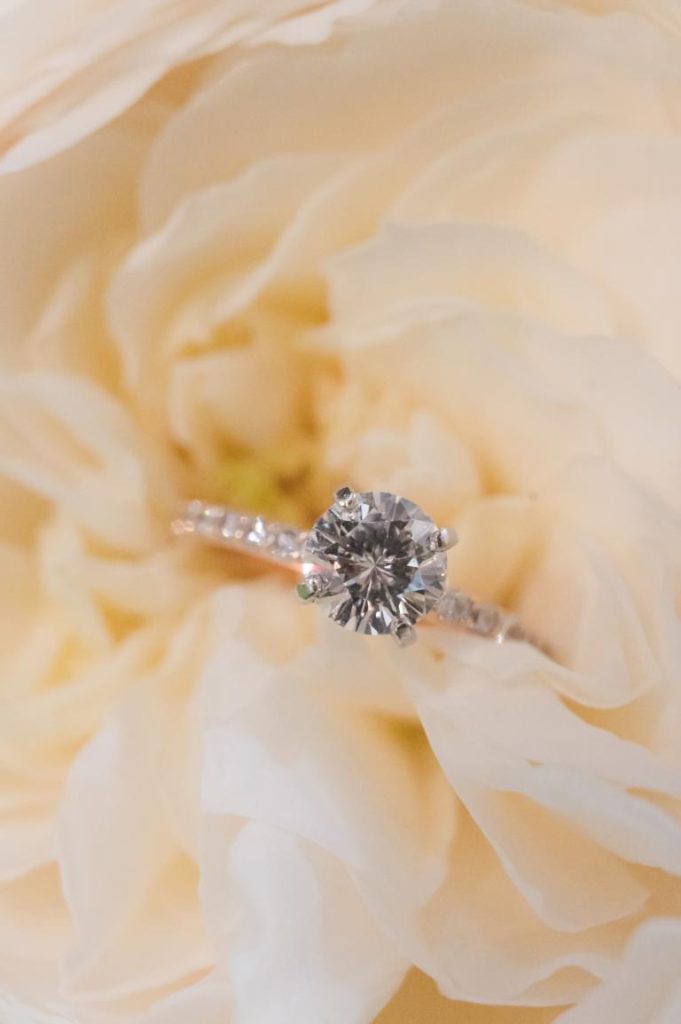 close up of engagement ring sitting in white rose