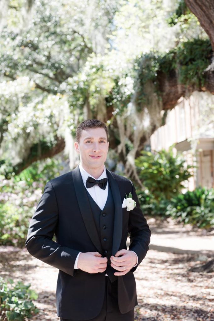 groom in tuxedo buttoning jacket