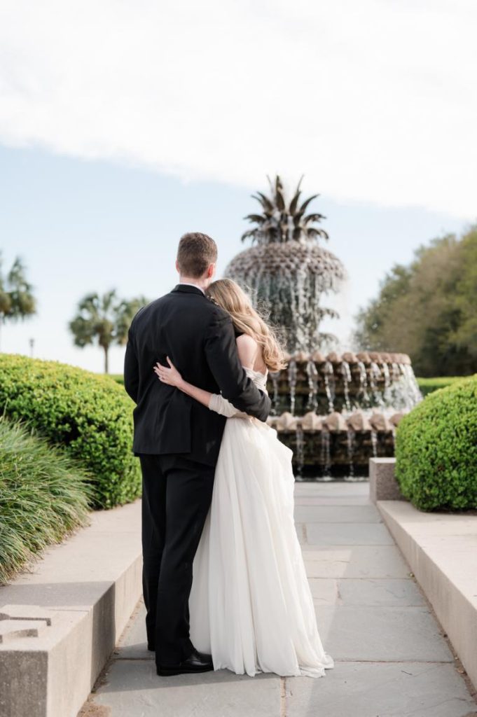 Newlyweds look at Pineapple Fountain with backs to camera