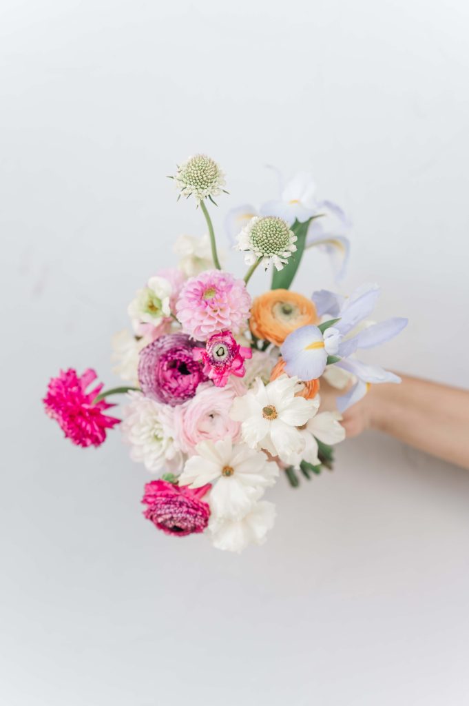 colorful spring wedding bouquet held against wall