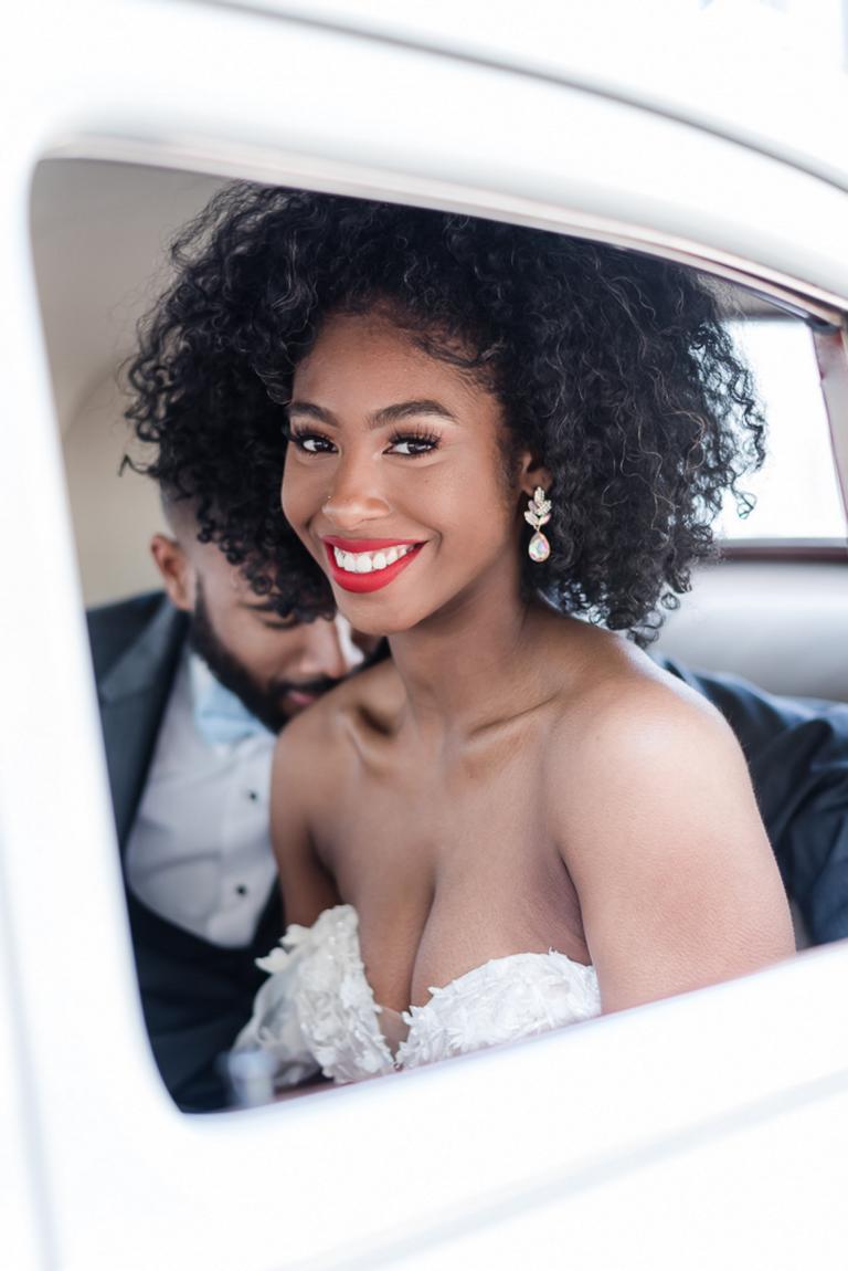 beautiful bride smiles through window of get-away car