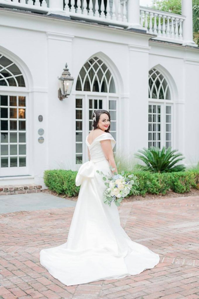 Bride standing outside of Lowndes Grove framed by arched window
