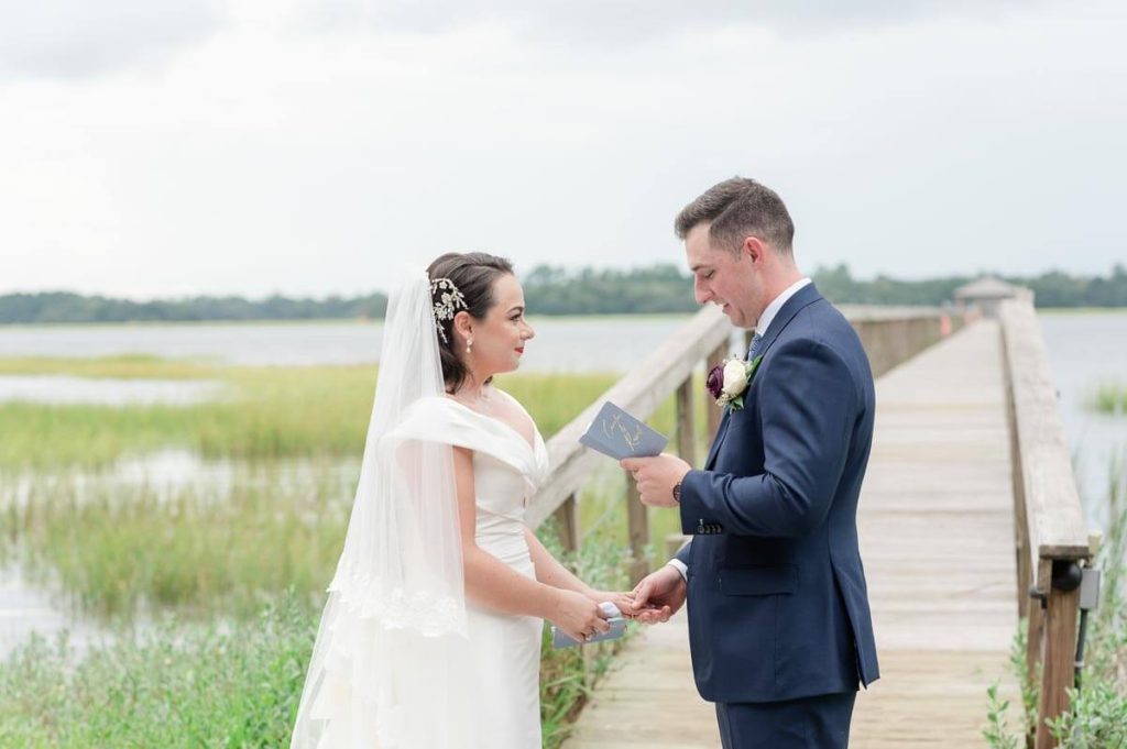 Bride and groom reading vow books on Lowndes Grove dock