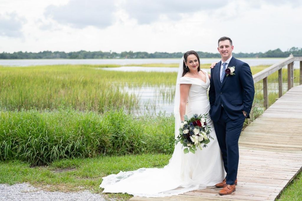 Newlyweds stand on dock at Lowndes Grove