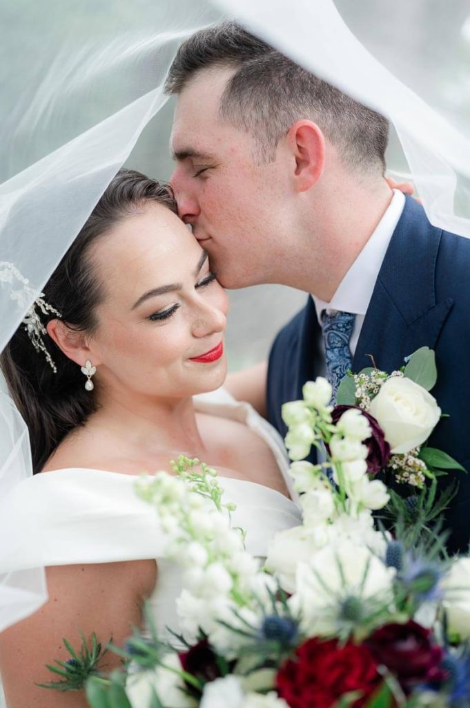 Newlyweds nuzzle under wedding veil