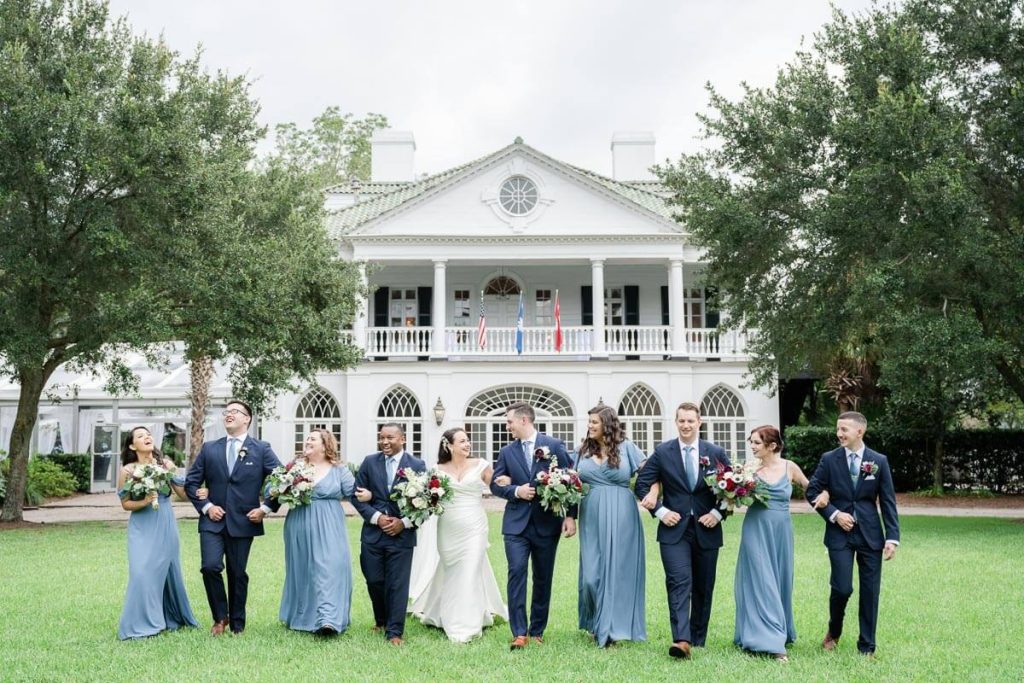 Wedding party walks arm in arm in front of Lowndes Grove House