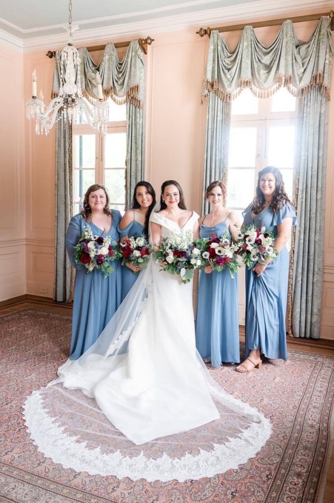bridesmaids in blue dresses pose with bride inside historic home