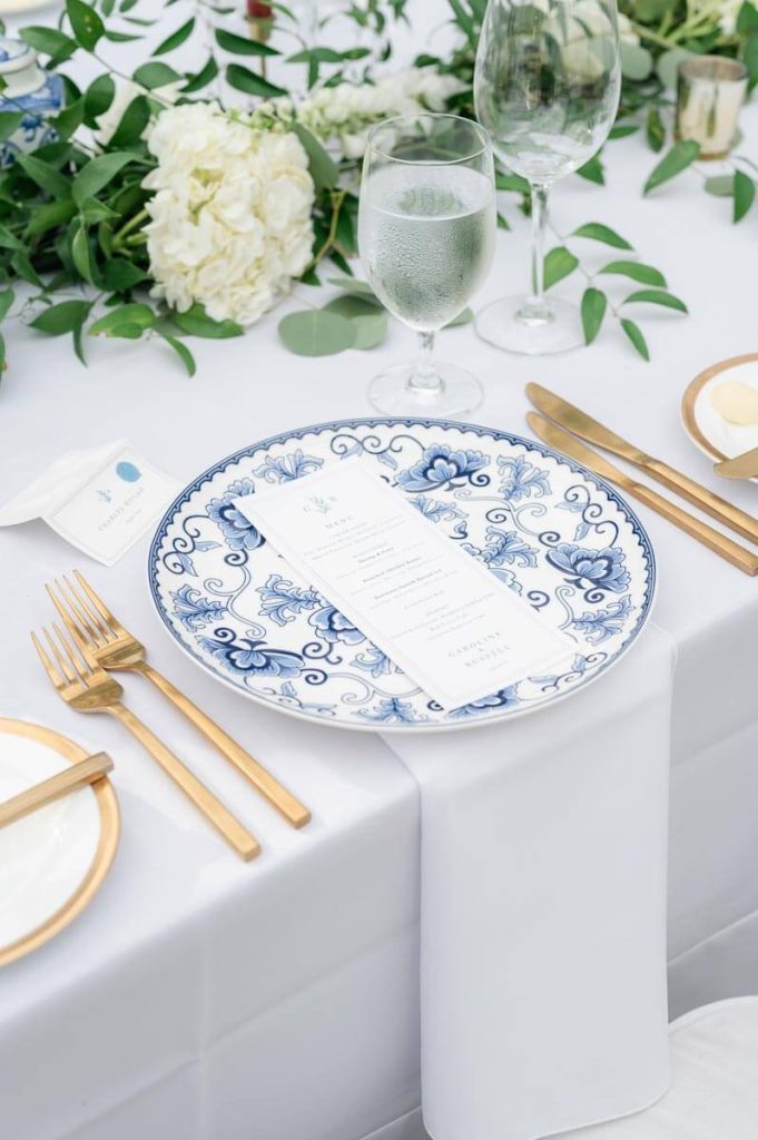 closeup of place setting with gold silverware and blue and white china plate