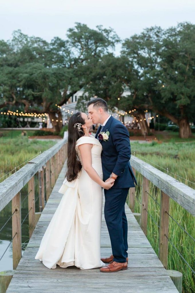 newlyweds kiss on dock overlooking wedding reception