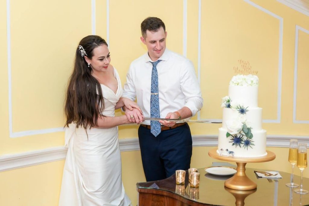 newlyweds cut wedding cake with sword