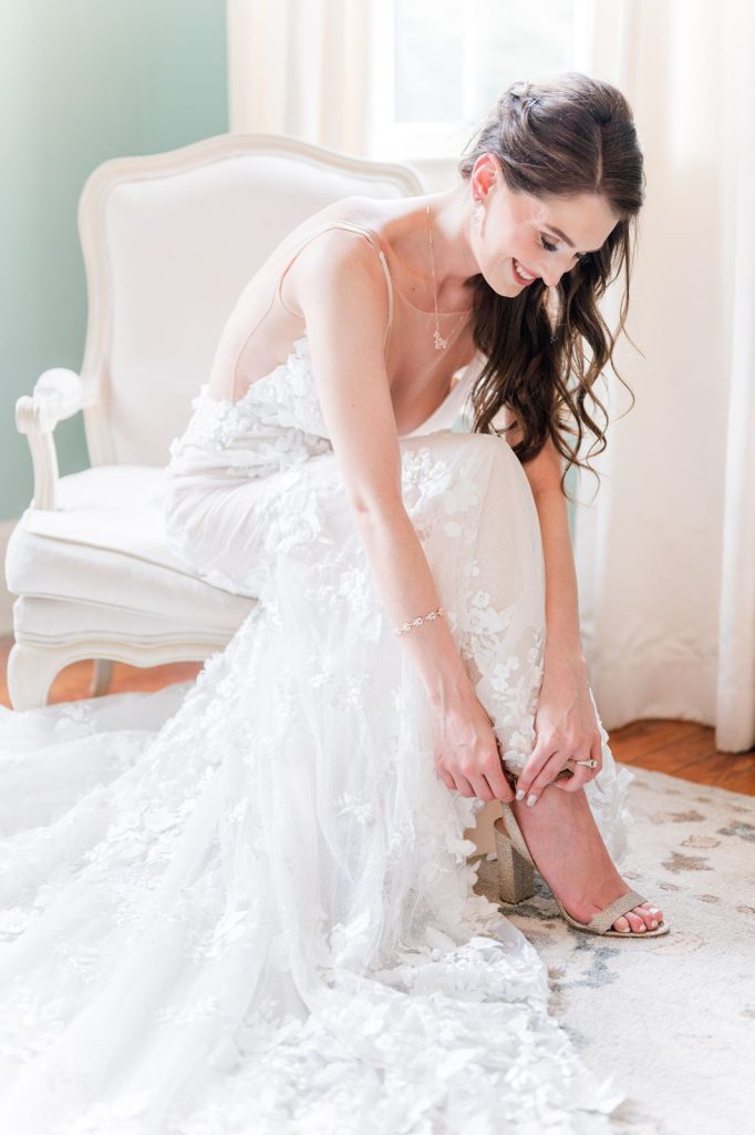bride sitting bending down to strap on shoes