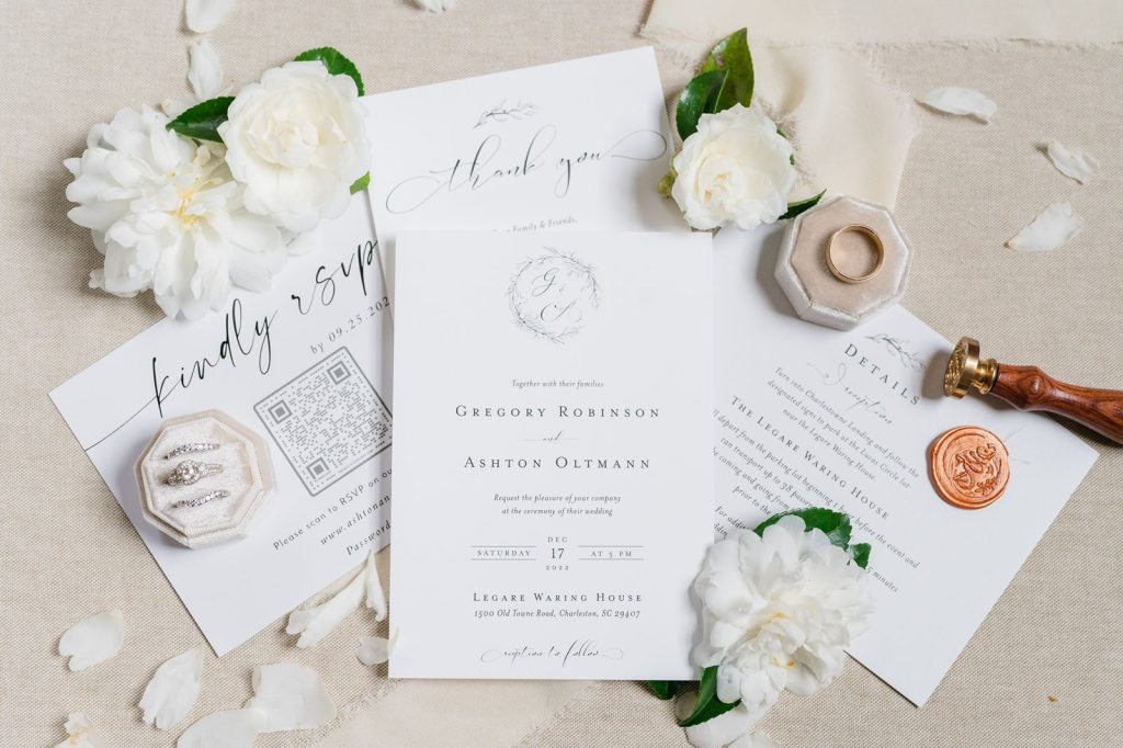 white wedding invitation with camellia flowers spread around