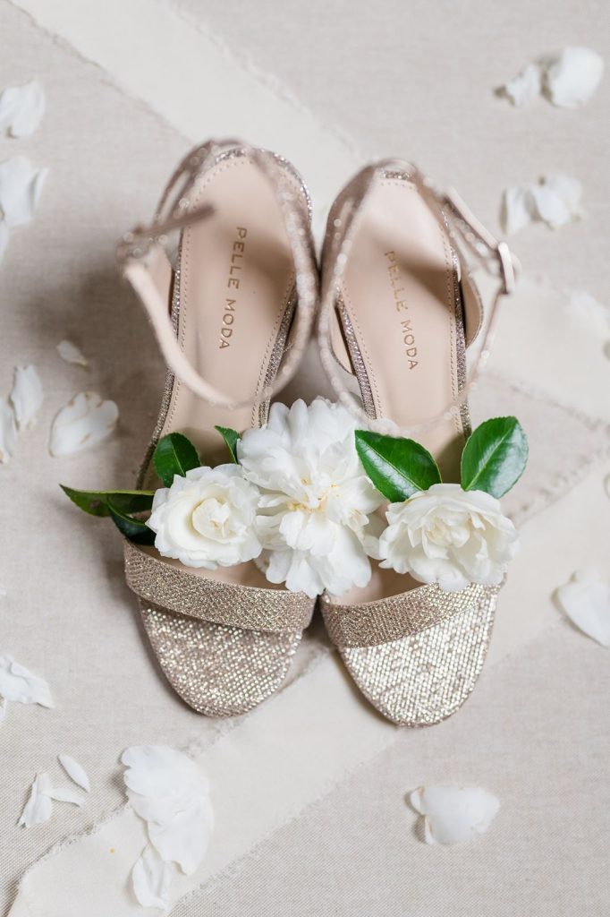 pair of gold glitter wedding shoes with flowers sitting on them