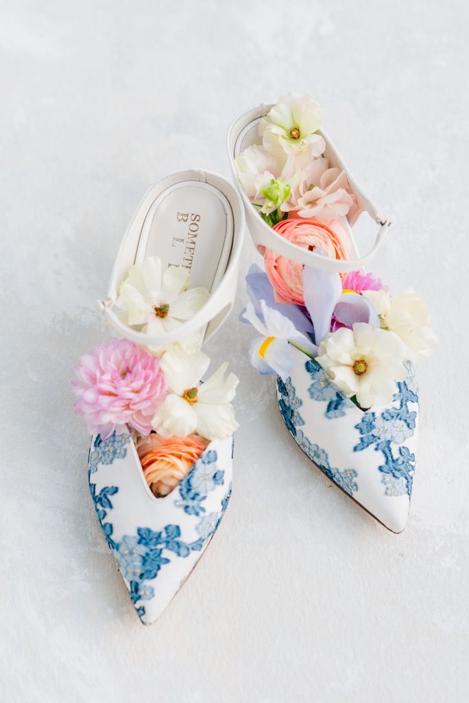 blue and white floral patterned wedding shoes with flowers in the shoes