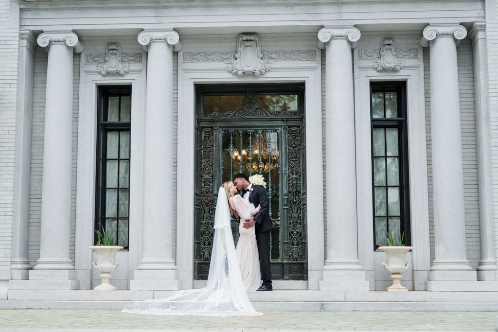 newlyweds nuzzle in doorway of mansion.