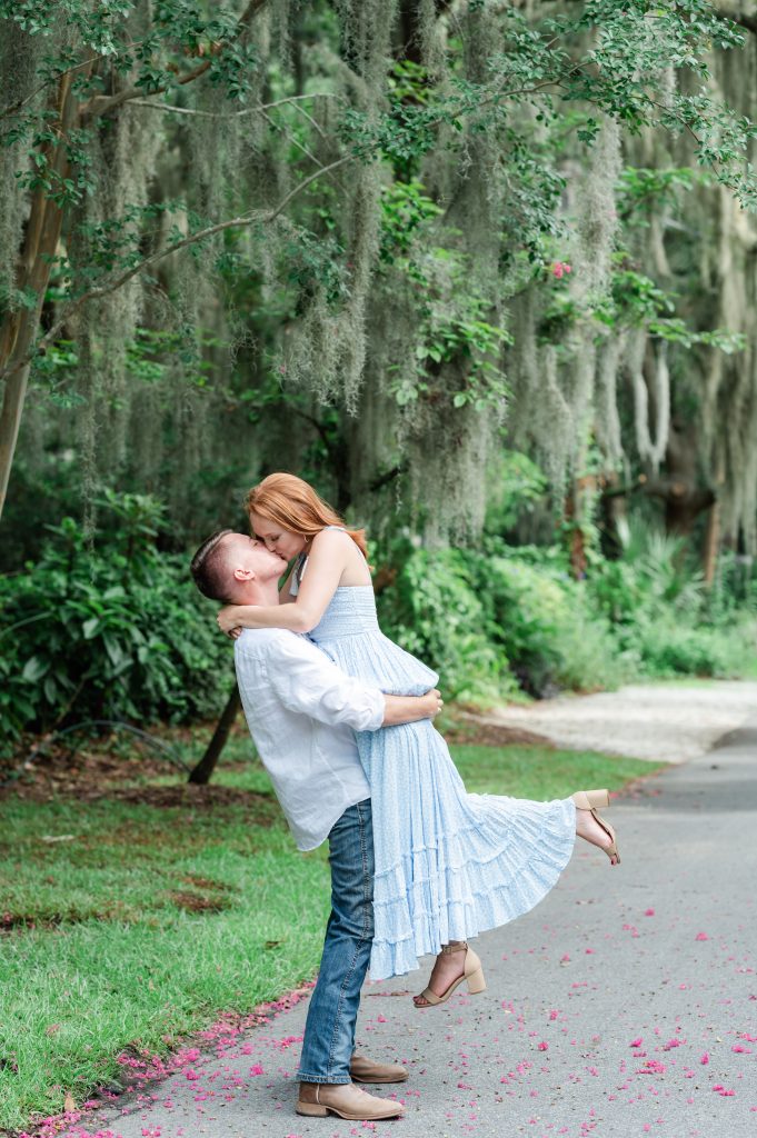 guy picking up girl and kissing her with Spanish moss in background.