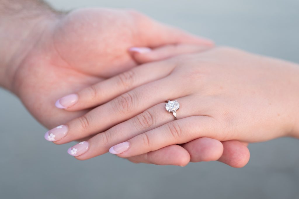 close up of woman's hand with new engagement ring on it in fiancé's hand