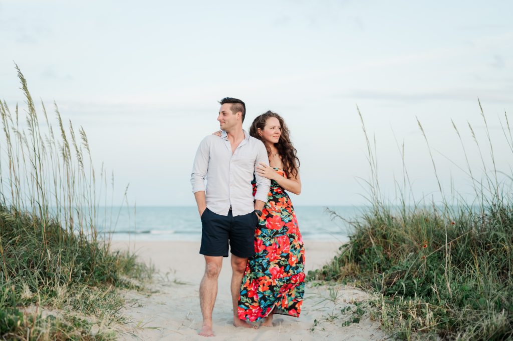 couple stand on sand dune at isle of palms beach looking out in different directions