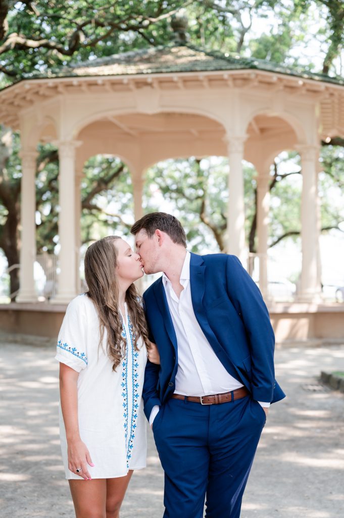 newly engaged couple kiss in front of gazebo