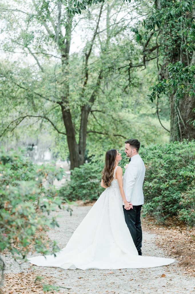 bride and groom look at each other while holding hands on gravel path