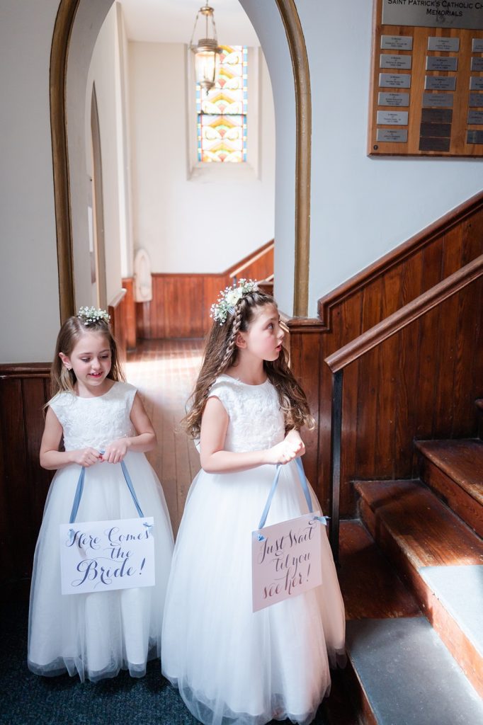 Flower girls holding signs right before they walk down the aisle