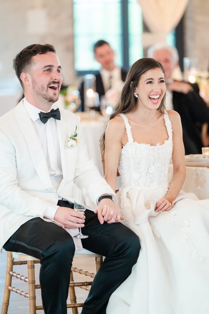 newlyweds laugh and hold hands during wedding toast