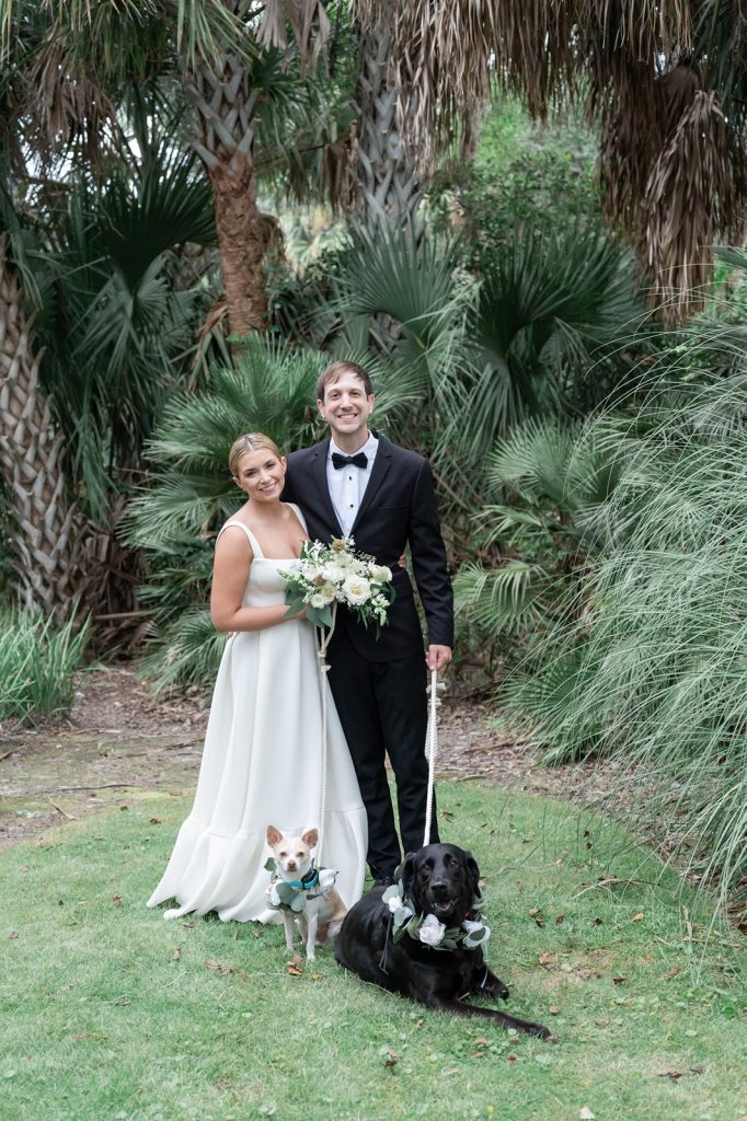 newlyweds smile at camera while posing with their two dogs