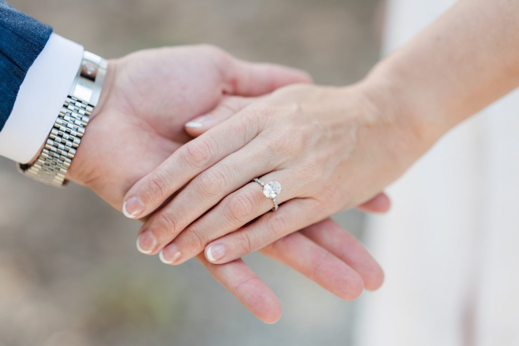 close up of couple holding hands showing off an engagement ring