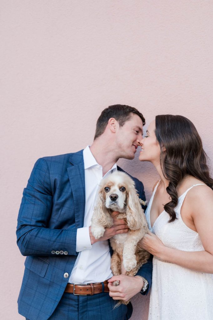 couple lean in for a kiss over their dog