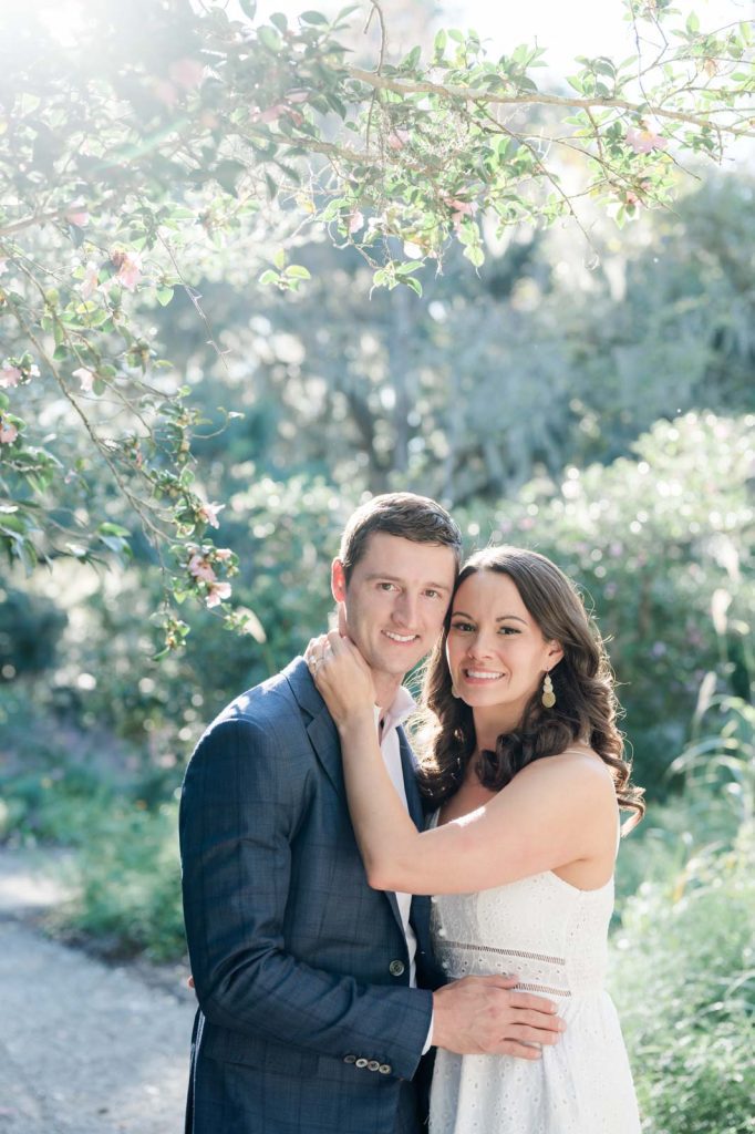 couple cuddle together in garden and look directly into camera