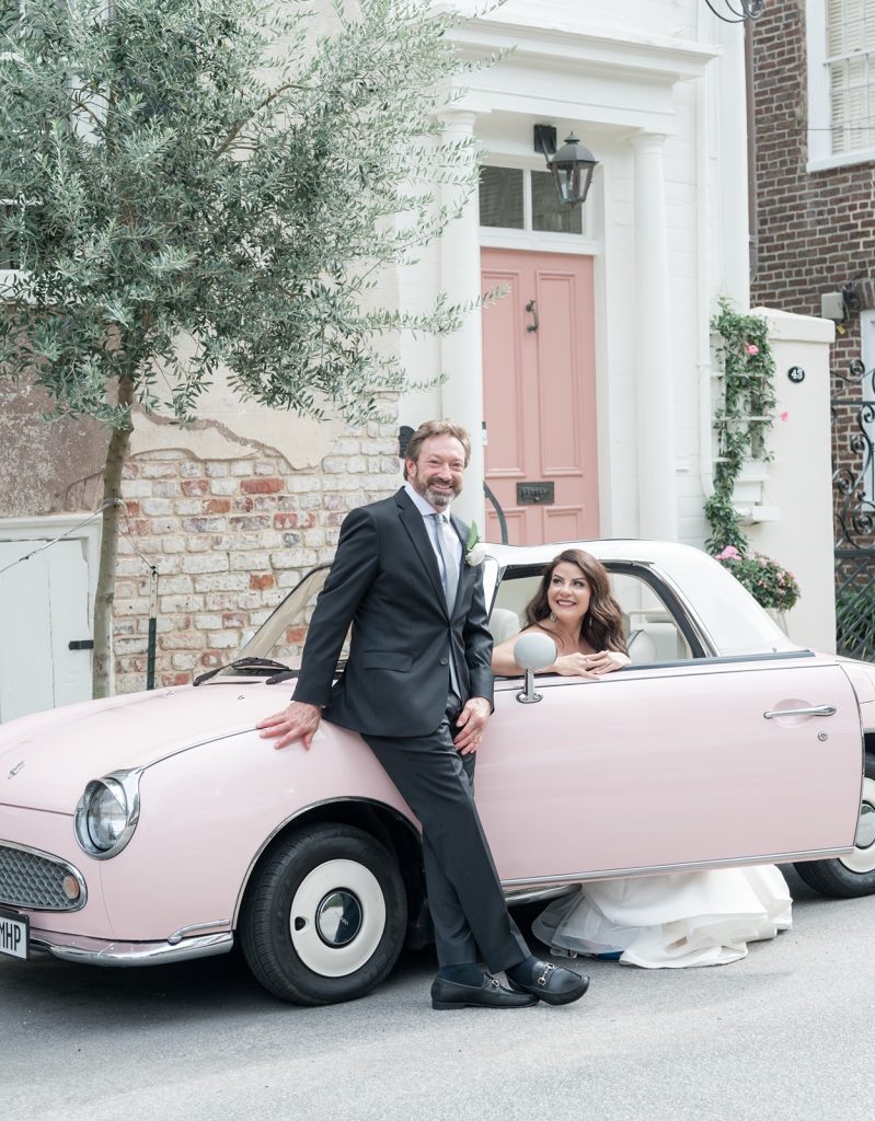 newlyweds pose in pink small car