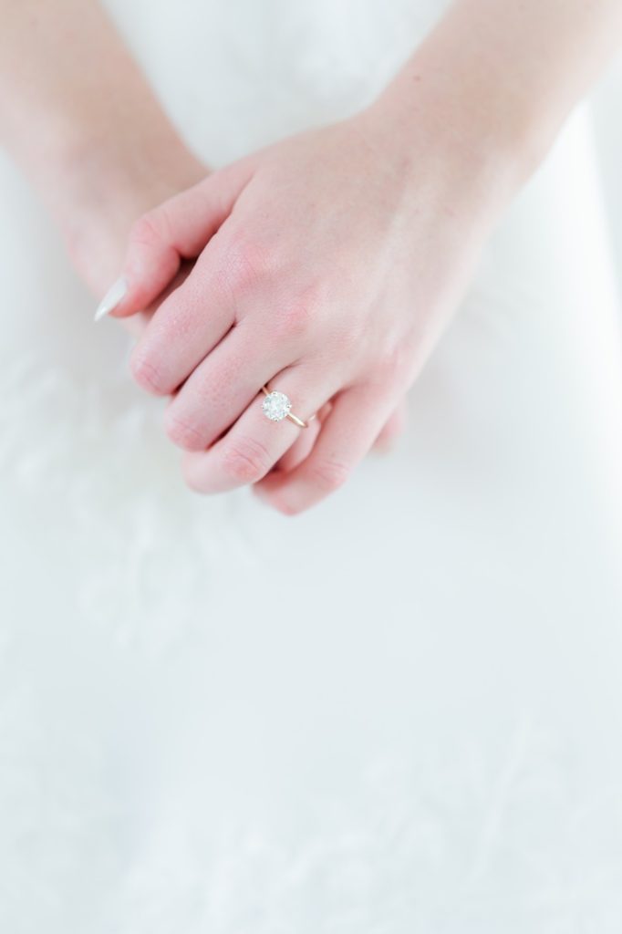 close up of solitaire engagement ring on bride's hands