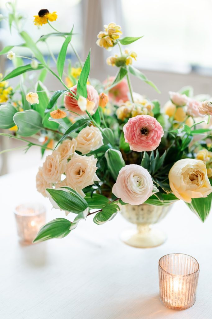 yellow and pink wedding floral arrangement sat on top of table
