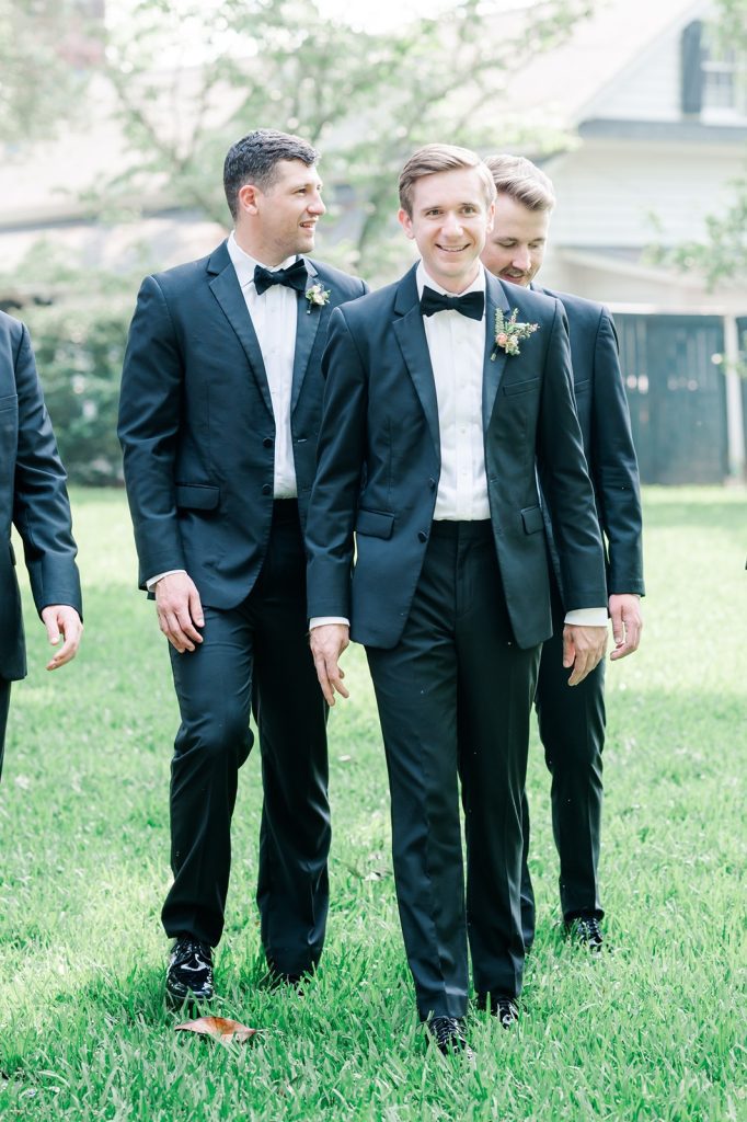 groom walking in garden with groomsmen