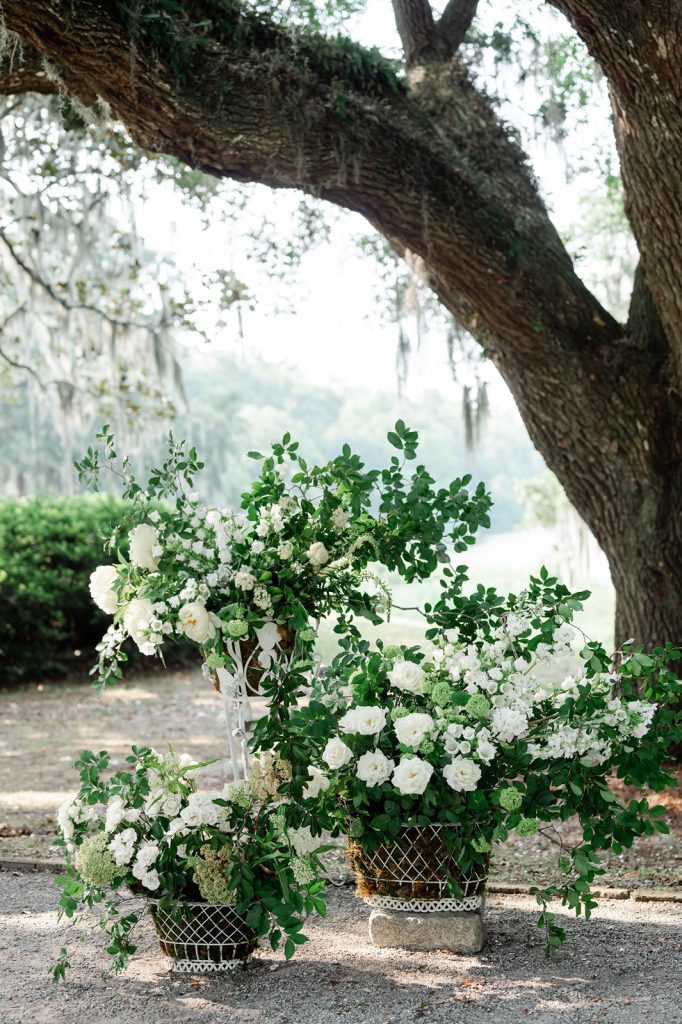 three arrangements of white florals at wedding ceremony site