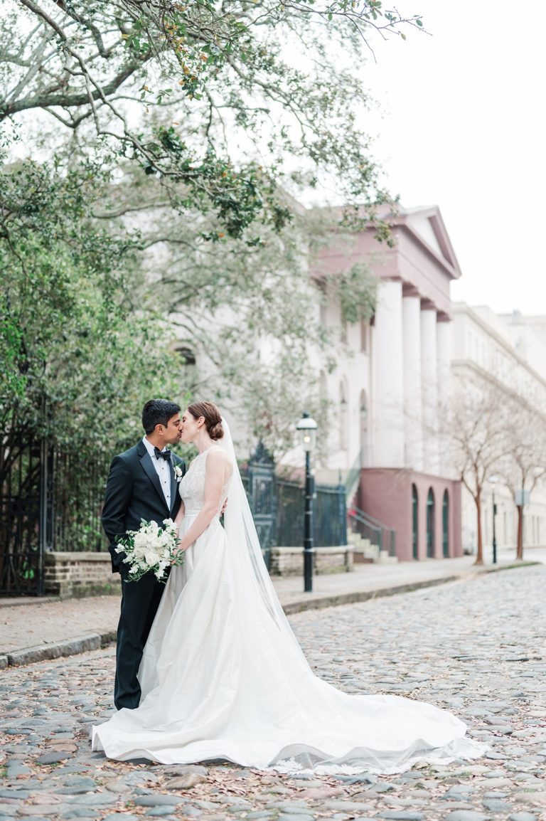 newlyweds kiss on cobblestone street in Charleston