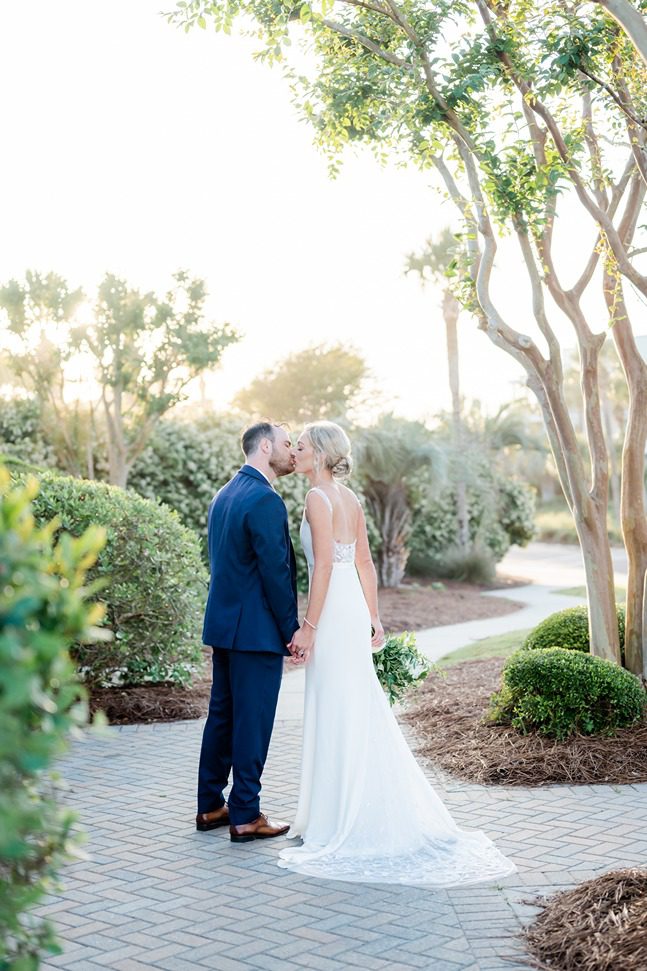 newlyweds kissing while being backlit by the sun